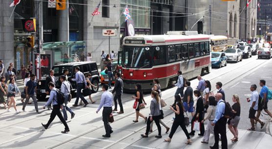Pedestrians cross a busy intersection in downtown Toronto, Canada, where economic growth has moderated this year (photo: KathrynHatashitaLee/iStock)