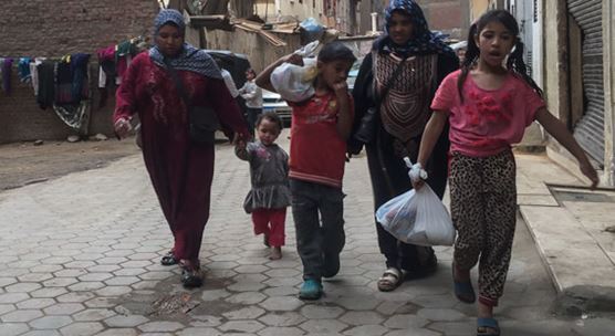 Two women walk back home after taking a bag during the distribution of staple commodities as part of an effort to mobilize voters during the last two days of Egypt's 2018 presidential election, in the working class neighborhoods of Meet Oqba and Ard al-Lewa, located in central Giza, Egypt, March 28, 2018 (photo: Islam Safwat/NurPhoto/Sipa USA)