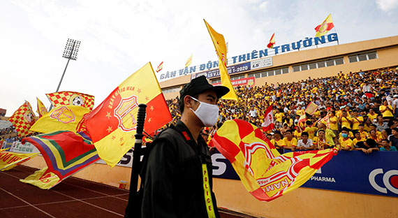 A police officer walks past soccer fans at a match in early June, after the Vietnamese government eased a nationwide lockdown following the COVID-19 outbreak. (photo: Reuters/Kham)